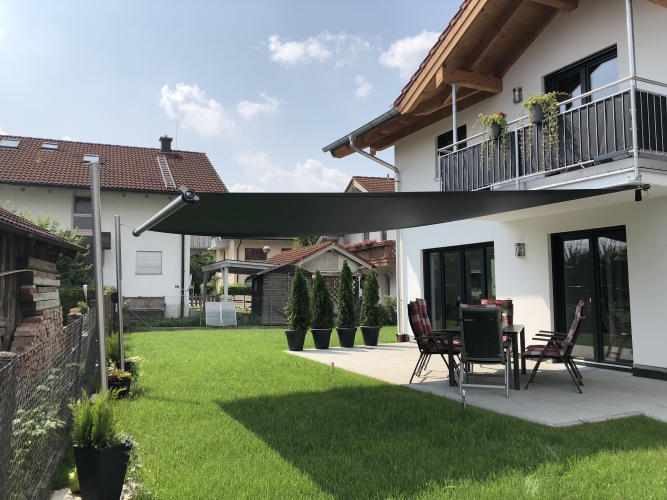 Modern weißes Haus mit Balkon, Markise, Gartenmöbeln und gepflegtem grünen Rasen