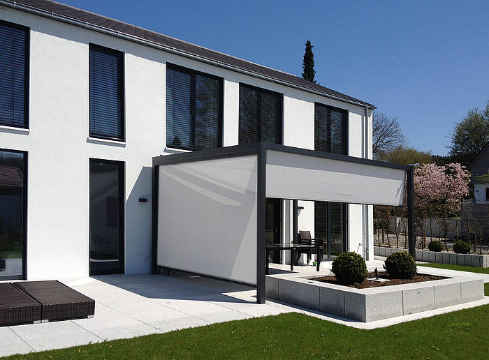 Modern weißes Haus mit großen Fenstern und einer eleganten überdachten Terrasse